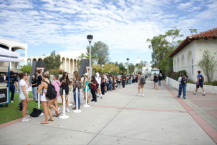 Dozens of students wait in a long line outside Google Gemini booths during the campus event, surrounded by SDSU buildings.